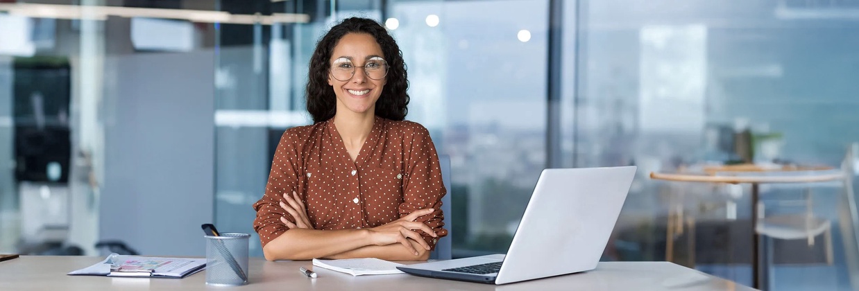 Lachende Frau vor Laptop am Schreibtisch