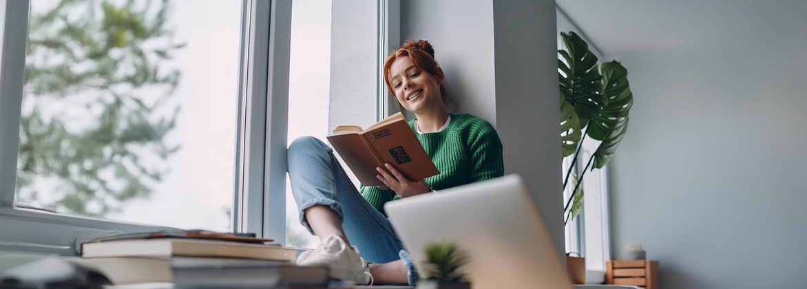 Juristin sitzt am Fenster und liest ein Buch