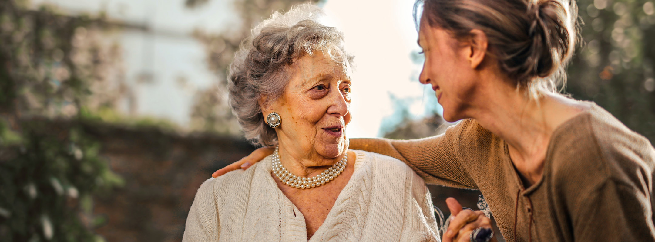 Eine junge Frau und eine alte Frau lachen sich an.