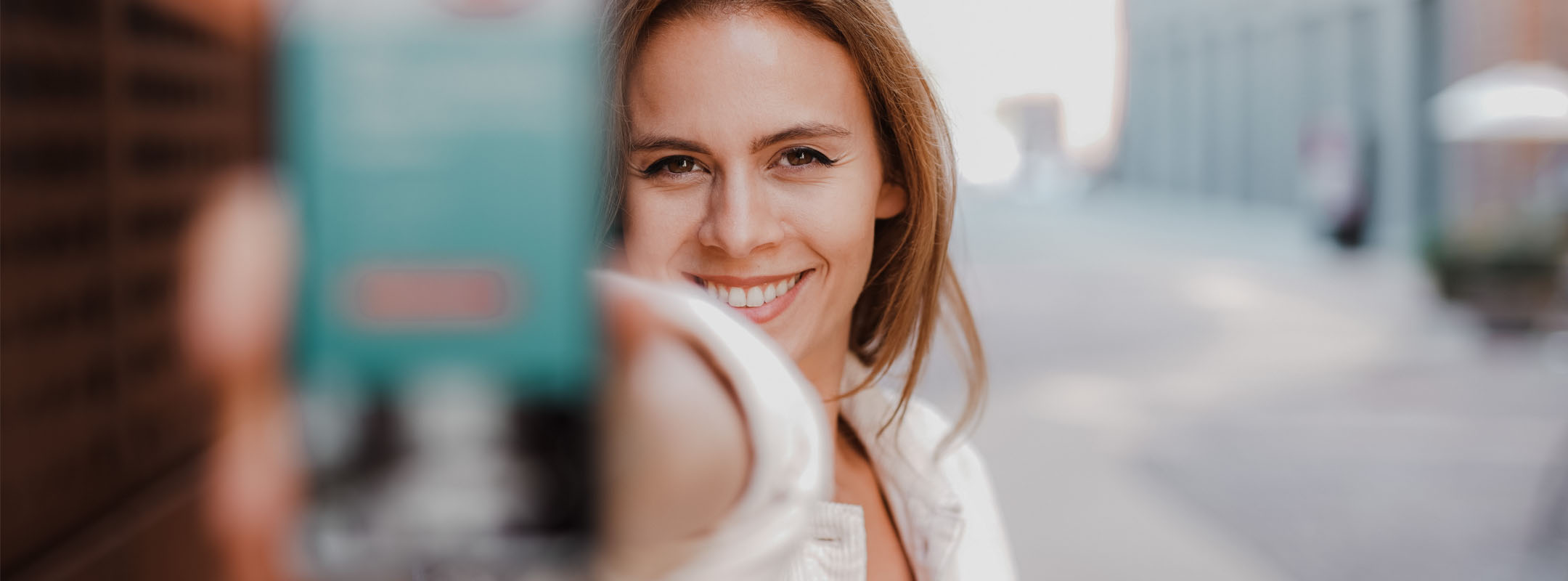 Ein junge Frau hält ihr Smartphone in die Kamera