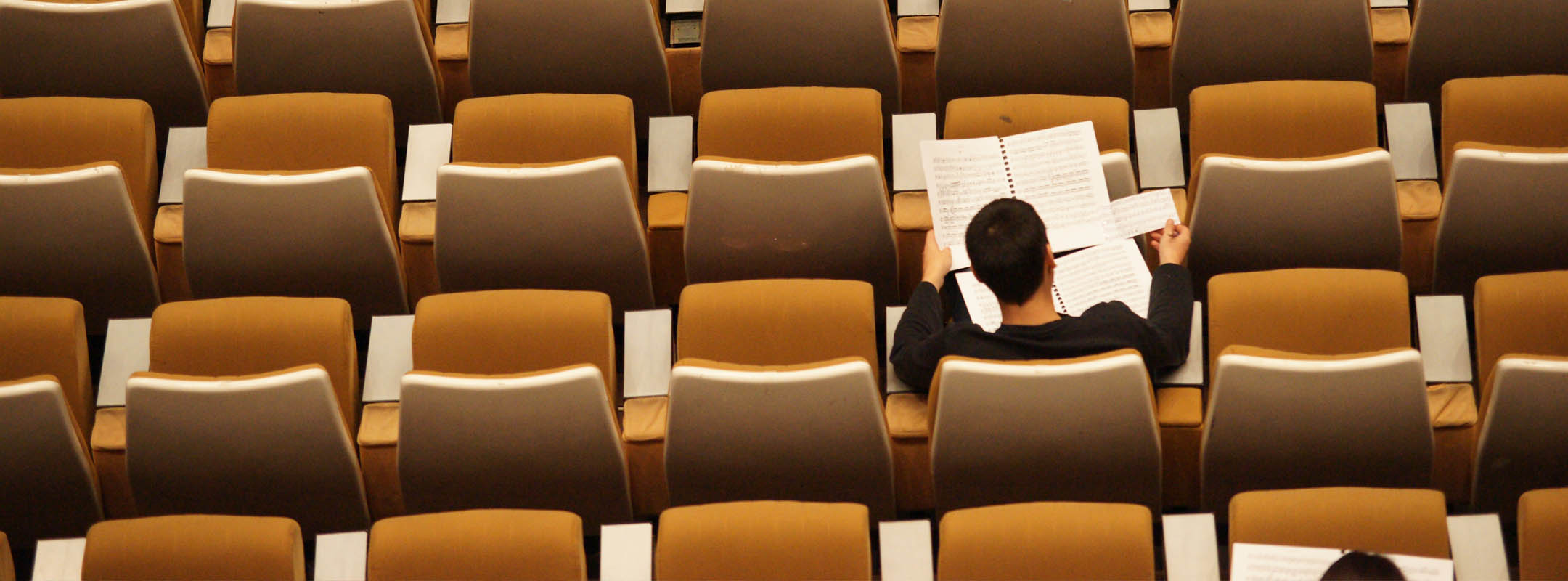 Ein Mann sitzt in einem leeren Hörsaal und liest etwas