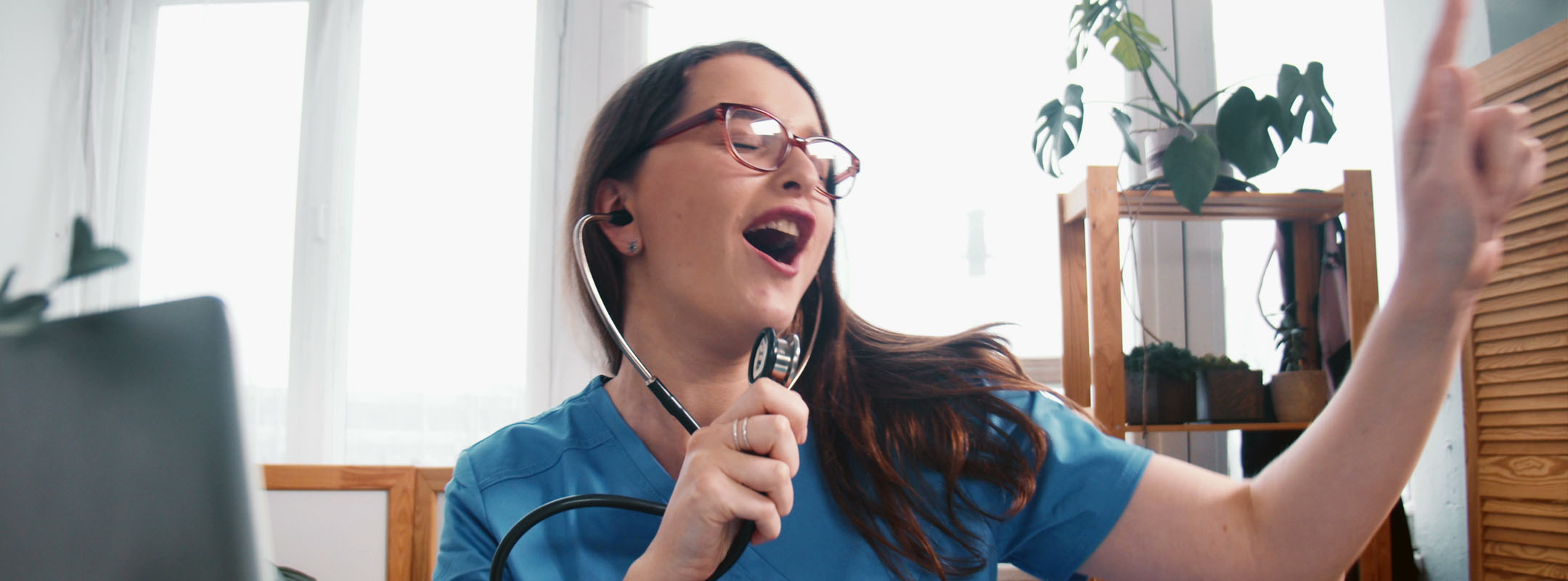 Eine Pflegekraft nutzt ein Stethoskop als Mikrofron und singt