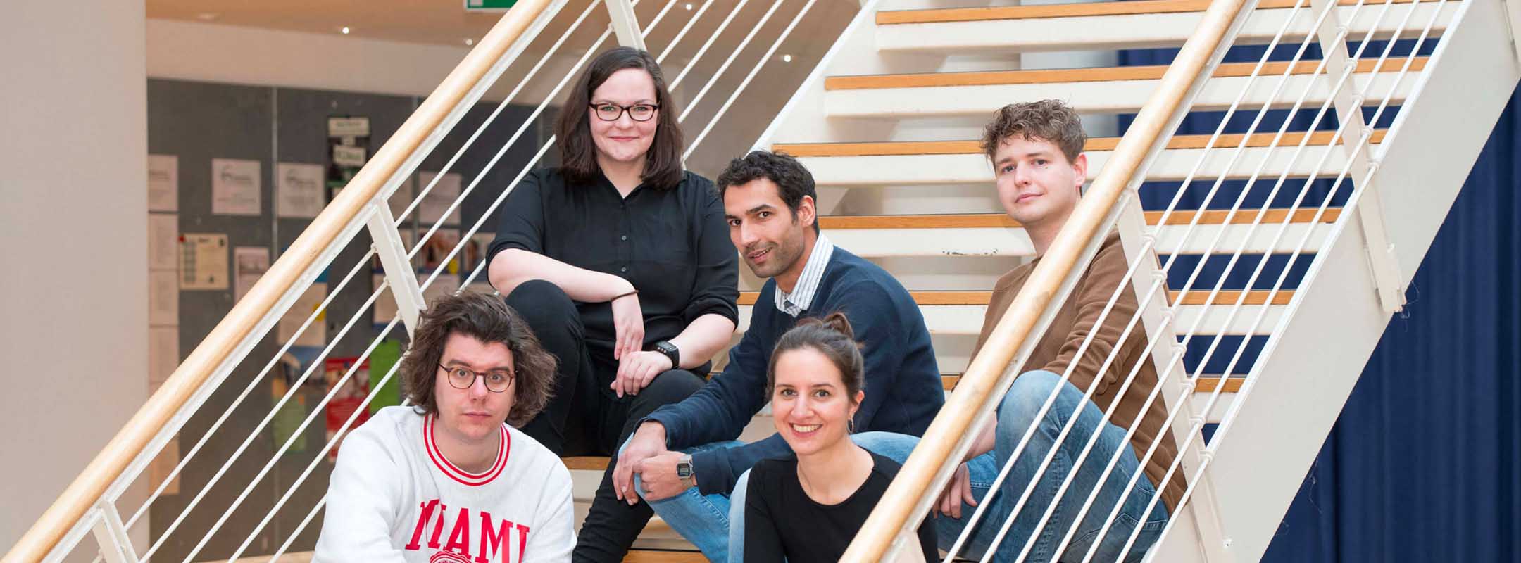 Das Team des Übergabe Podcasts sitzt auf einer Treppe