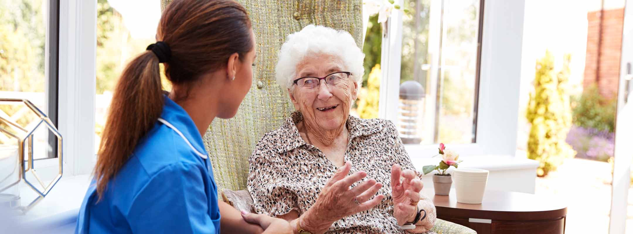 Eine Pflegerin spricht mit einer alten Frau