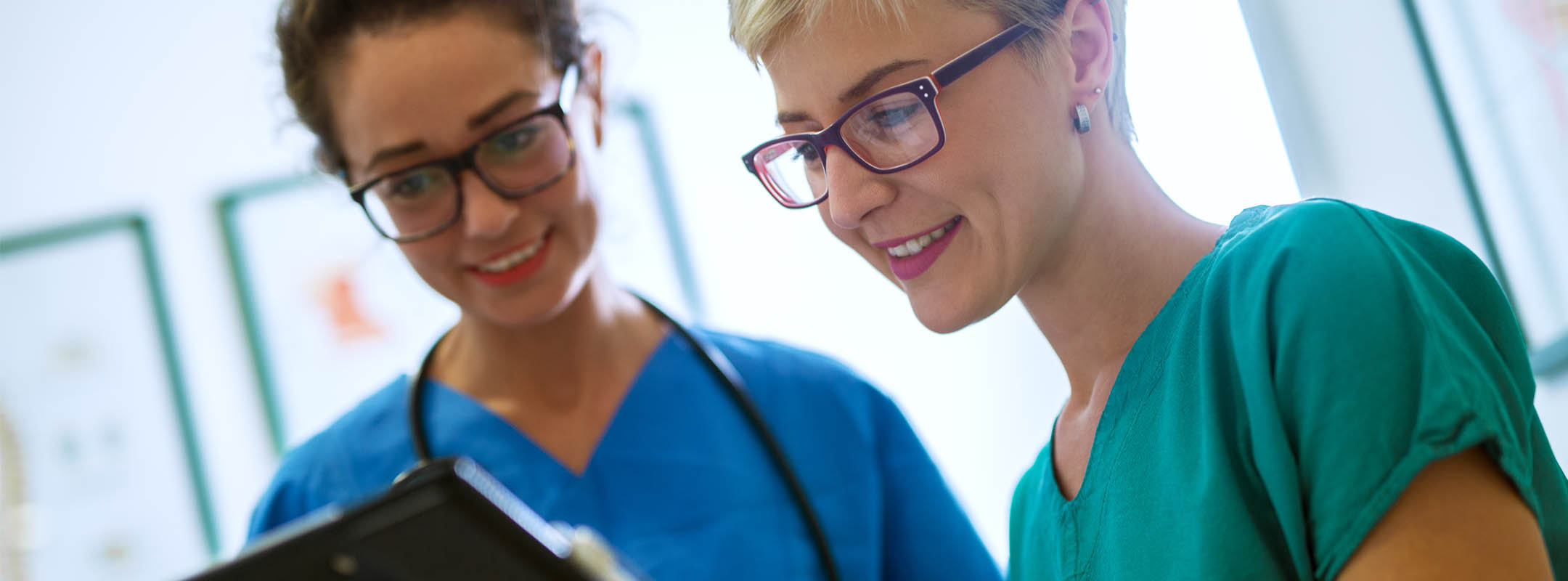 Zwei Krankenschwestern blicken gemeinsam auf Notizen