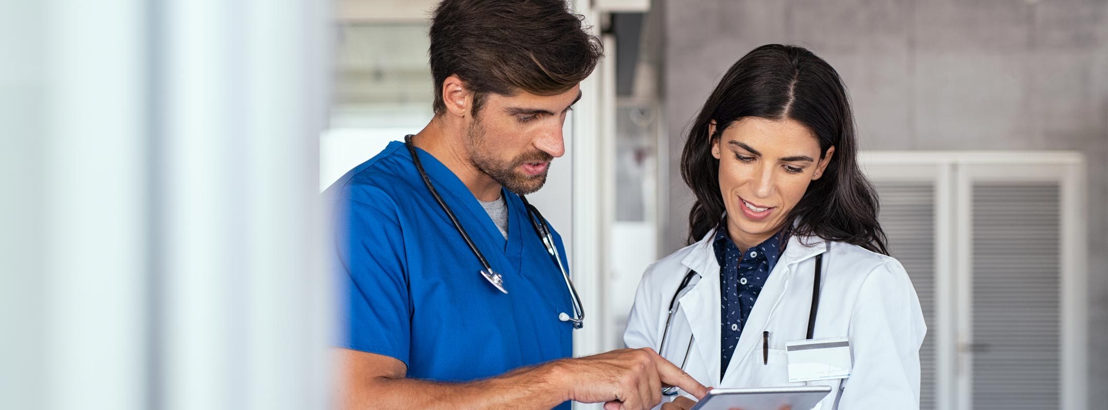 Eine Ärztin und ein medizinischer Angestellter blicken gemeinsam in Unterlagen