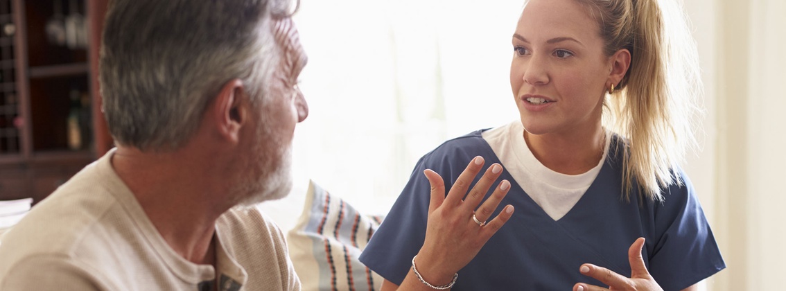 Eine Pflegerin erklärt einem älteren Mann etwas
