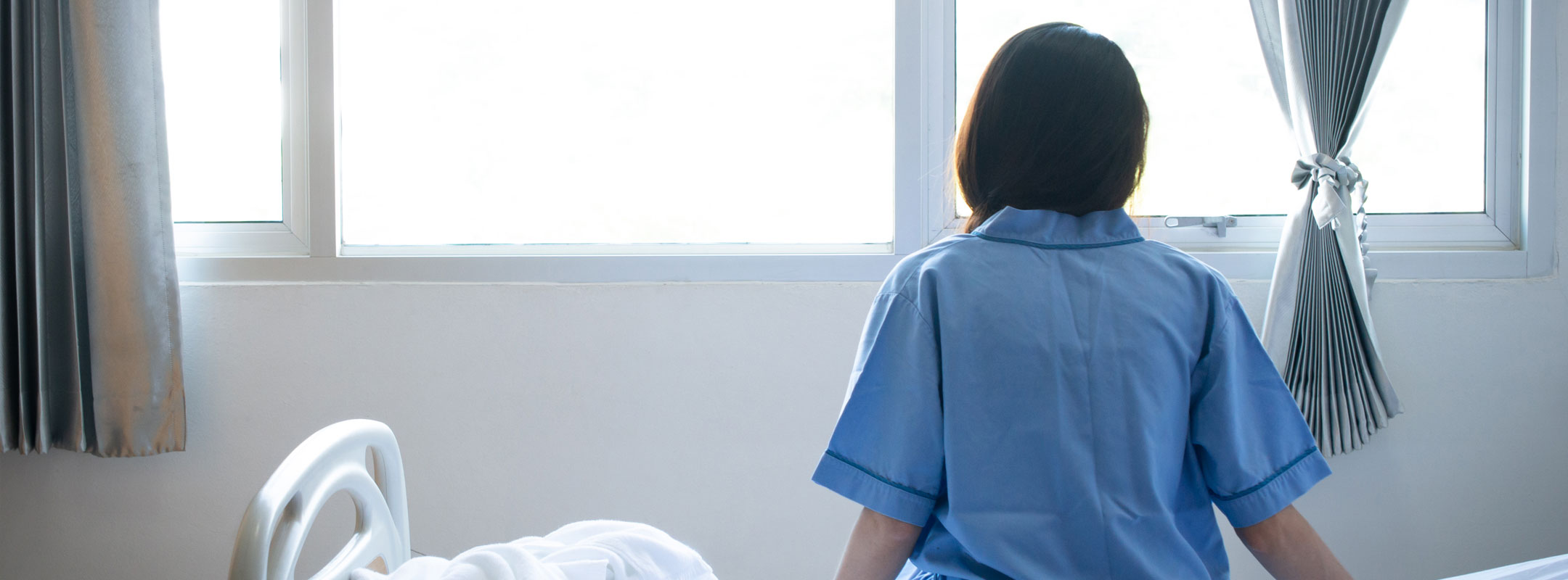 Eine Patientin sitzt auf ihrem Bett und schaut aus dem Fenster