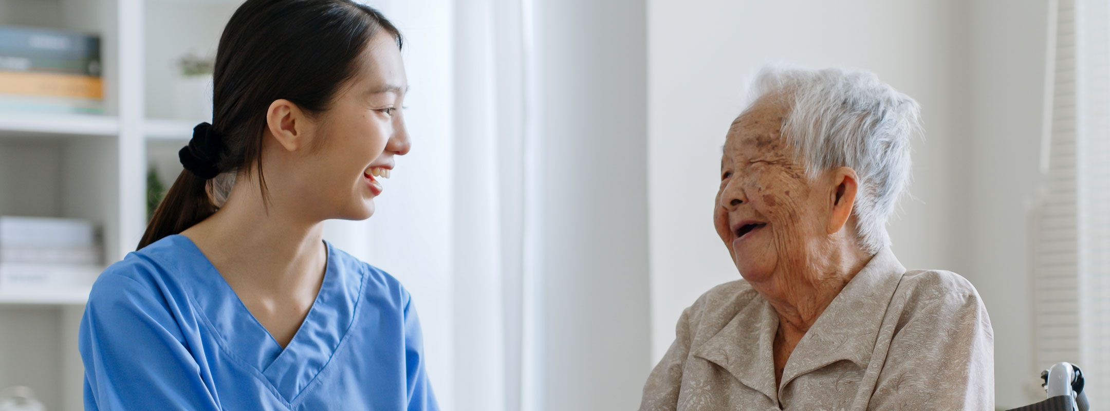Eine Pflegerin und eine alte Frau lachen