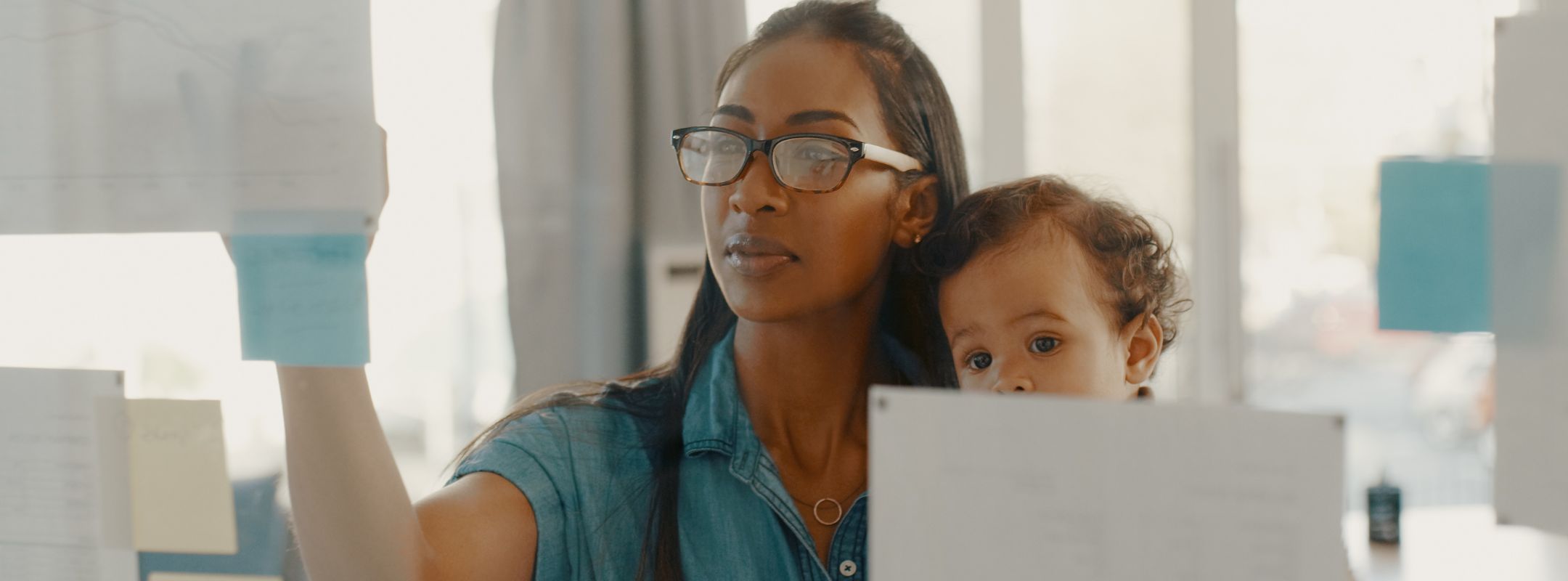 Eine Frau sitzt mit ihrem Baby vor dem Laptop